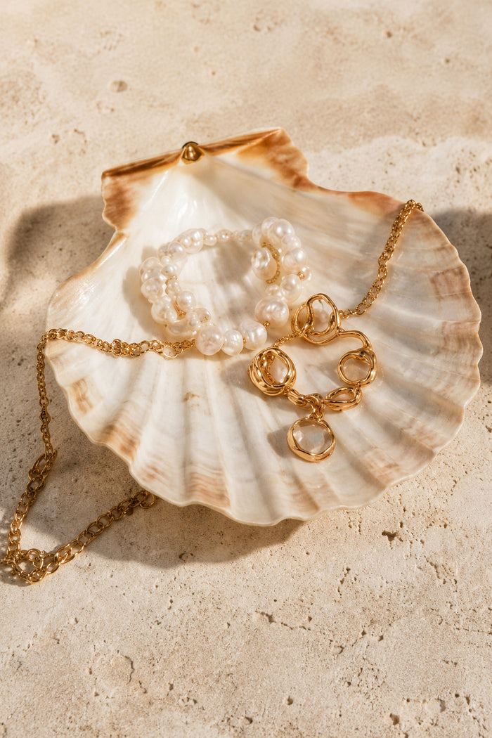 Pearl and gold jewellery resting on a shell